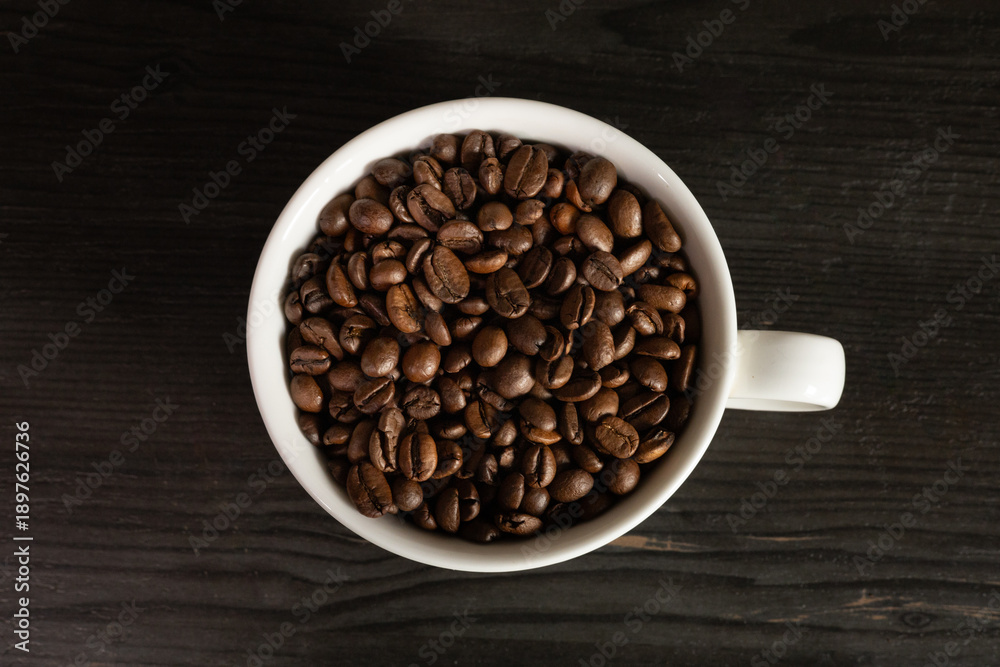 Fototapeta premium White coffee cup filled with coffee beans, minimal still life, clean background, coffee concept.