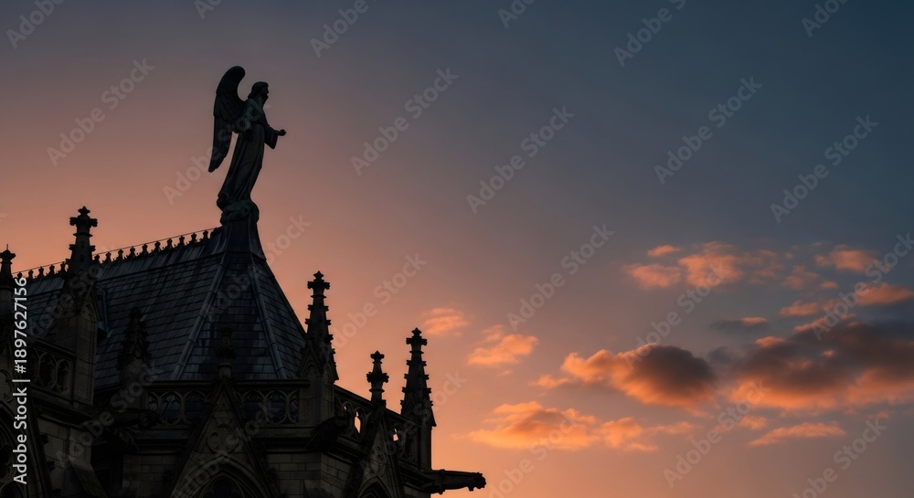 Fototapeta premium Silhouette of angel sculpture on gothic church rooftop. Religious art against an expressive sunset sky for spiritual or architectural design.