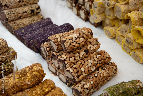 Assorted traditional turkish lokum, sweet rolls with chocolate, cashew, pistachio, and other nut coatings, displayed at a market