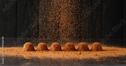 Φωτογραφία Cocoa powder falling over chocolate truffles with reflection on black background