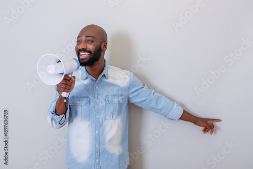 Fényképezés Black man speaking into megaphone announcing news and pointing finger engaging w
