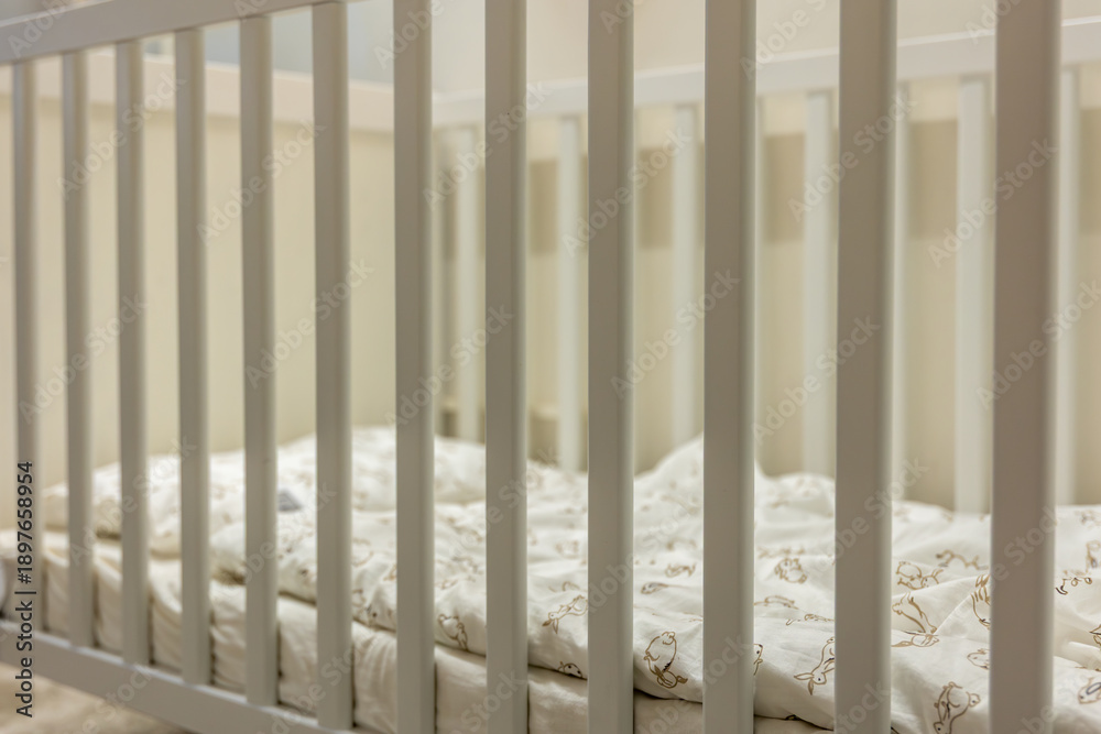 Fototapeta premium Baby crib with soft bedding closeup. Gentle safety.