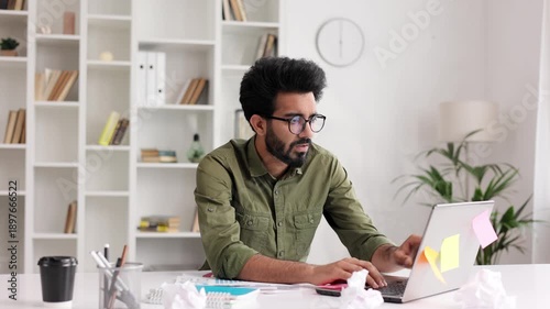 A tired young Indian boy gets angry from the number of tasks, crumples up the paper and throws it away, tries to calm down. Stressful work and study, overtasking.