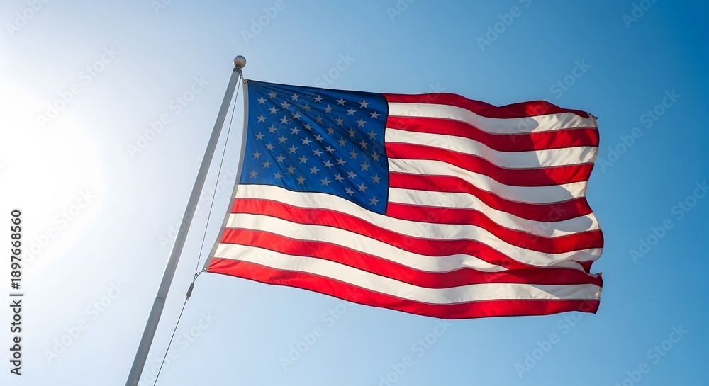 Obraz premium American Flag Waving Proudly Against Bright Blue Sky - Symbol of USA Patriotism and Freedom