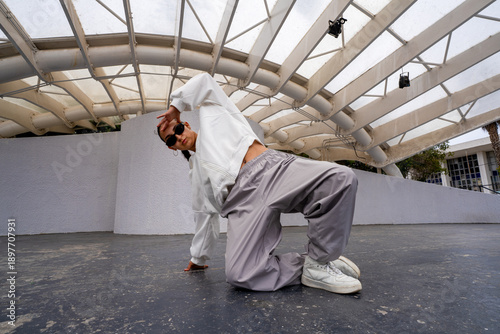 Фотография Woman performing a dynamic breakdance move on an urban stage