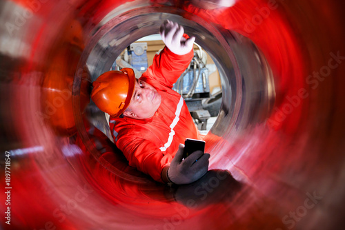 Картината върху платно Industrial worker inspecting inside large metal pipe during maintenance work