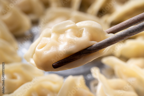 Close up of hot steamed dumpling being picked up by chopsticks in a steamer pot