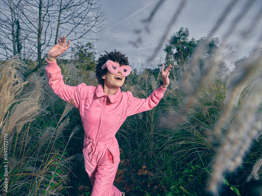 Fototapeta premium Playful child outdoor pink mask grass imagination nature movement sunshine, exploration and wonder in a carefree moment captured in a sunny natural setting outdoors