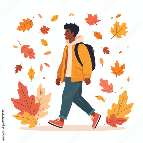 A young man walking through a sea of falling autumn leaves on a crisp day