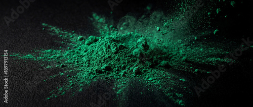 A dramatic close-up of vibrant green powder exploding and scattering across a dark, textured background.