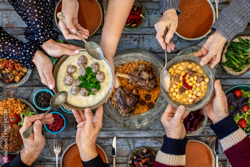 Iftar, break the fasting at holy Ramadan with family, top view of a dining table at iftar time when many human hands sharing their meal. 