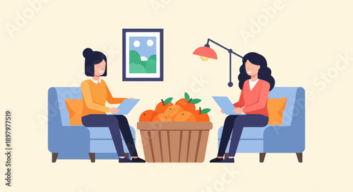 Two women sit on sofas with a basket of fruit between them