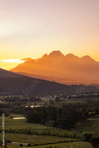 Sunset over mountain range and vineyard landscape in Cape Winelands, South Africa, showcasing wine region and scenic beauty for travel