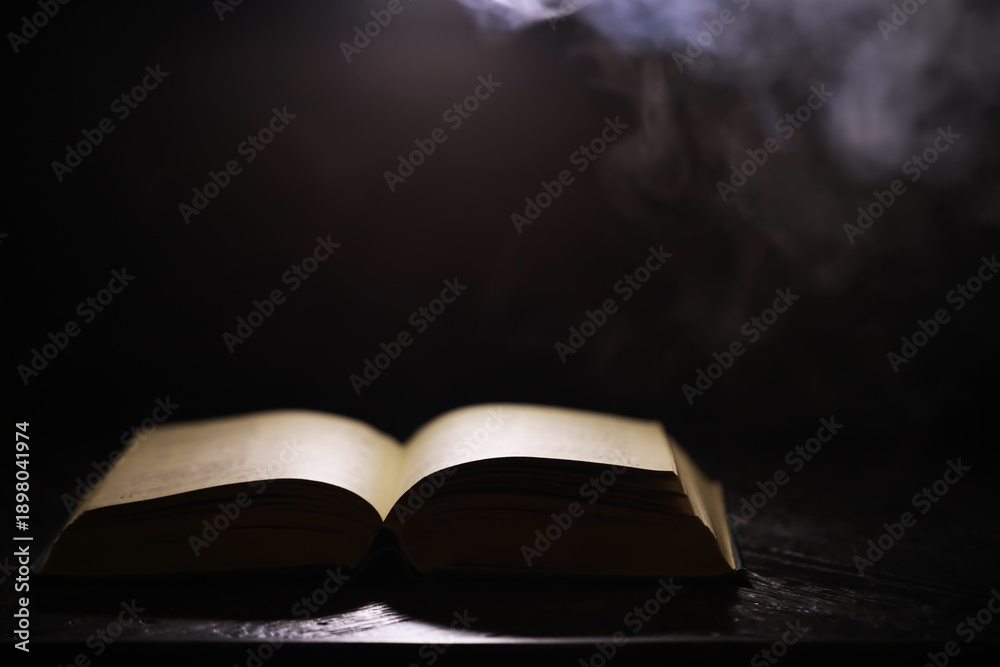Fototapeta premium Mystical Open Book in Dark Smoky Atmosphere Dramatic Lighting