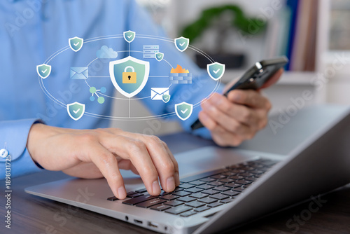 Cybersecurity concept illustrating data protection, cloud security, and network defense. Business professional working on laptop and smartphone with secure digital network icons.