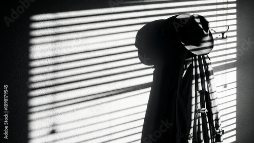 Film noir silhouette of coat and hat with window blind shadows