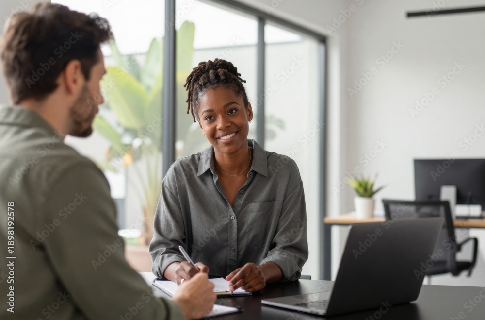 Fototapeta premium Job Interview: Smiling African American Woman Interviewee with Interviewer in Modern Office Setting, Candidate Writing