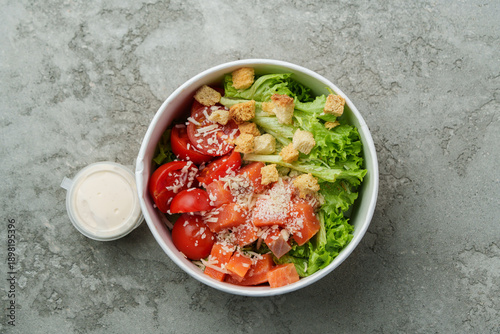 Cuadro en lienzo Fresh salad with lettuce, tomatoes, croutons, and dressing on a gray surface