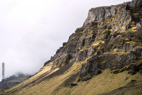 Shot of a highland cliff with layered rock strata and vivid green moss, emphasizing the dramatic geological history of the region. Ideal for themes related to geology, travel, and nature.
