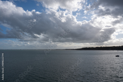 Foto Large paysage marin sous un ciel partiellement nuageux, avec de vastes étendues d’eau calme et une ligne côtière visible à l’horizon