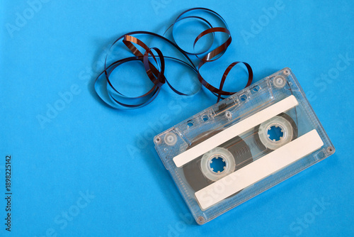 Obraz na płótnie Analog cassette tape with brown magnetic ribbon unwound and tangled, resting on