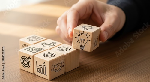 Hand Completing a Wooden Cube Puzzle with Business Icon Drawings