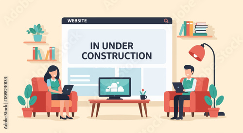 Two people work on laptops next to a website under construction sign