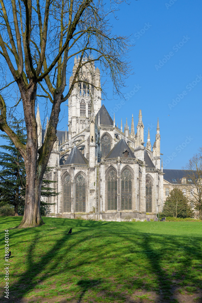 Fototapeta premium Saint Ouen Abbey Church with wide green lawn in front, architecture captured on bright spring day, architecture lines clear against blue sky, historic building shown in calm natural light