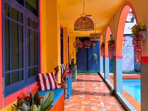 Fotografie Colorful tropical corridor with vibrant arches, patterned tiles, hanging lamps, plants, and poolside architectural design