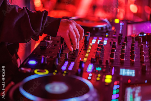 Schilderij op canvas A DJ adjusts controls on a professional digital mixer and turntable setup, surro