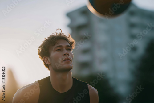 Athletic young man holding basketball at sunset, cinematic street sports portrait
