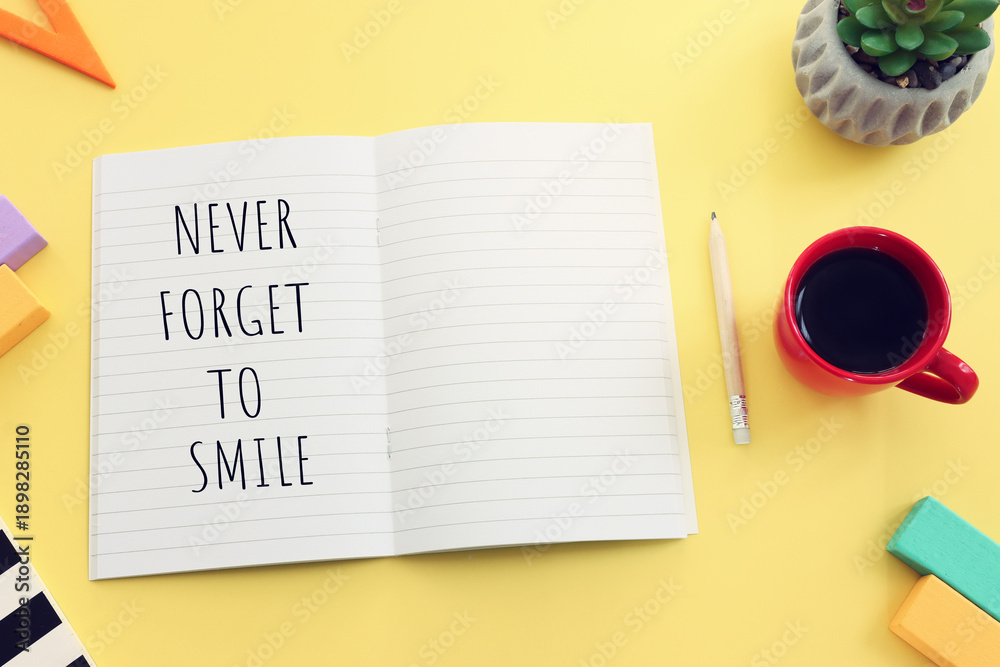 Naklejka premium Notebook with motivational text. Never forget to smile. yellow background