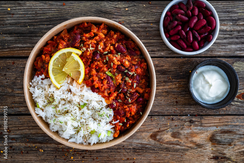 Photos Chili con carne with rice to go on wooden table. Top view