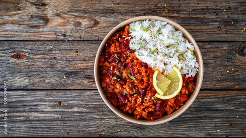 Fotografia Chili con carne with rice to go on wooden table. Top view