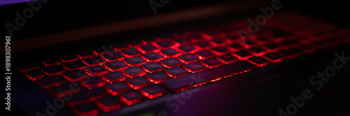 Fotografi A close-up view of a laptop keyboard illuminated with red backlighting
