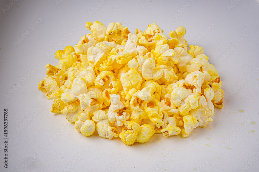 Obraz premium A delightful mound of fluffy popcorn rests on a white surface, perfect for sharing during film time
