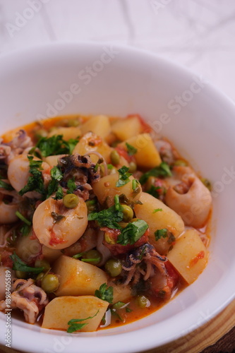 Primo piano di piatto con seppie, piselli e patate