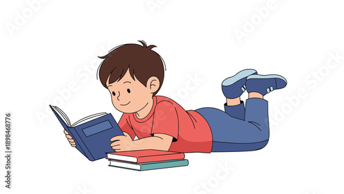 Young boy lying on his stomach on the floor while happily reading an interesting storybook with other books piled next to him.