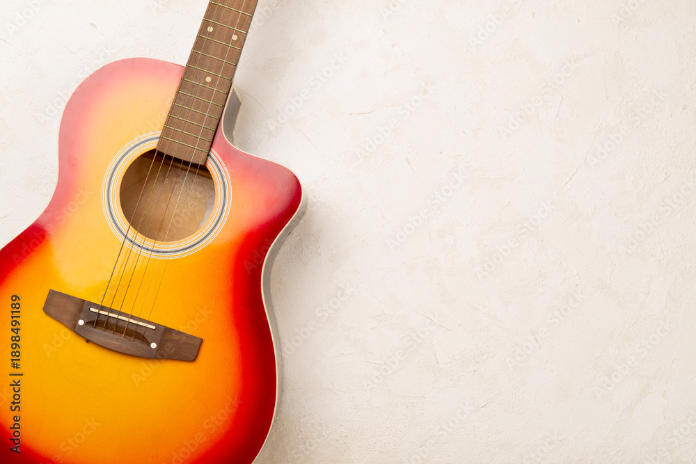 Fototapeta premium Bright acoustic guitar on concrete background, top view