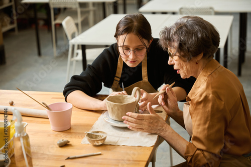 Two women in a ceramics studio making a clay bowl