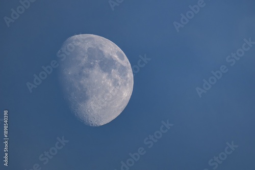 Detailed image of the waxing moon with visible craters and spots during the day, dividing line between the day and night sides of the moon visible, Finland