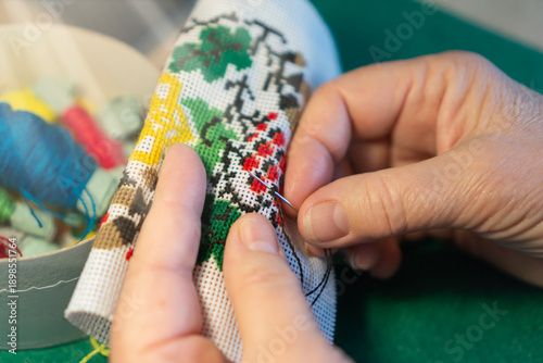 Foto close up of hands cross stitching on canvas traditional needlework hobby and cra