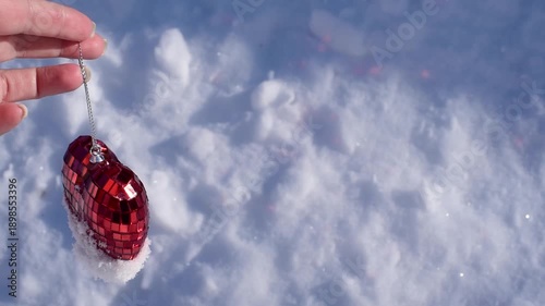 Close-up hand holding artificial heart in snow on snowy background,St.Valentines Day background video