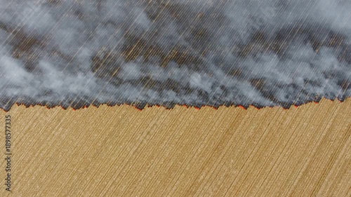 Aerial view of stubble burning spreads smoke across dry farmland causing severe environmental damage. Agricultural fire destroys soil health ecosystems and crops through harmful traditional practices.