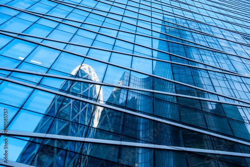 Corporate office architecture details in urban Paris with modern glass skyscraper facade reflection and geometric grid pattern under clear sky