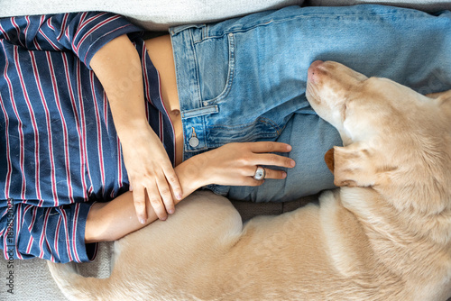 Photography A woman is laying on a couch with her dog on her lap