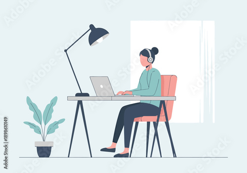 Young woman working remotely at home office desk with laptop computer and headphones focused on online tasks and learning