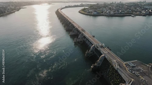Wallpaper Mural Aerial view of a long concrete dam curving across a bay, with a city on the horizon Torontodigital.ca