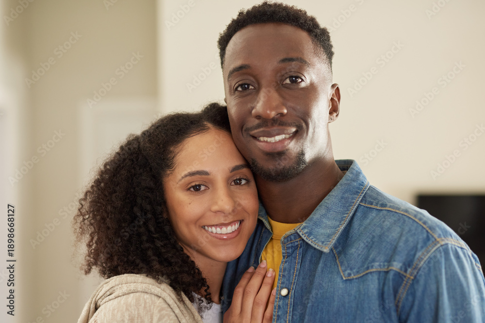 Obraz premium Young multiracial couple smiling while standing arm in arm at home