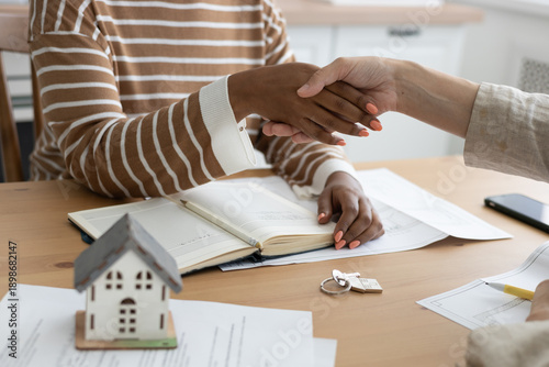 handshake between two people, conclusion of contract for sale of real estate. architectural and design project contract. buying or renting an apartment. miniature model of house stands on table.